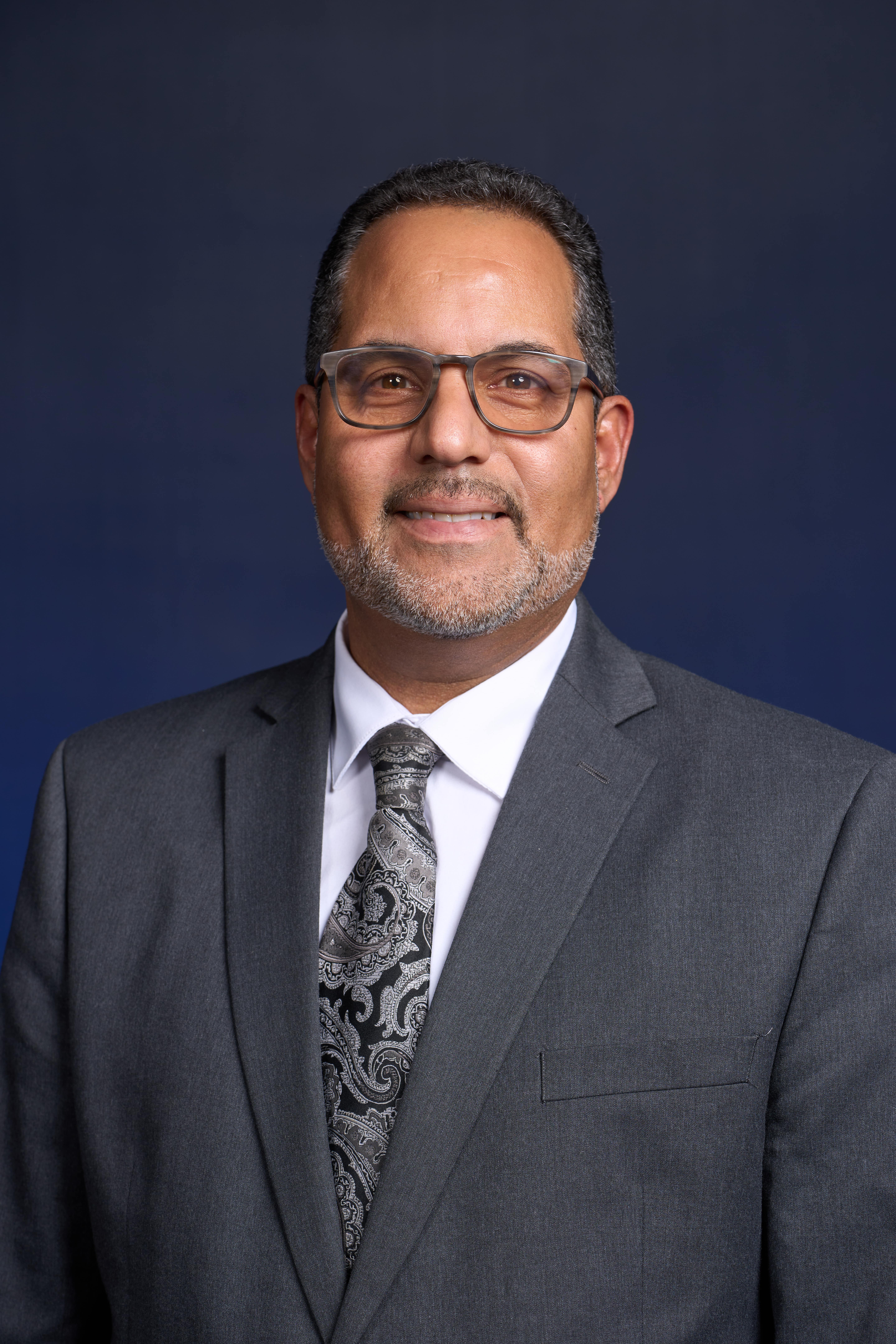 A headshot of Henry Ponciano wearing a suit and tie.