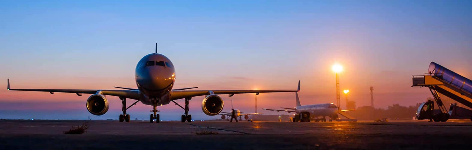 An airplane sitting on a runway at sunset.